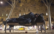 Una persona sense sostre dorm en un banc al costat de la Ciutadella