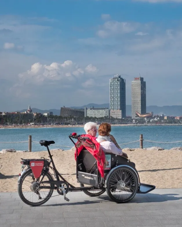 Tricicle amb dues persones grans davant del mar