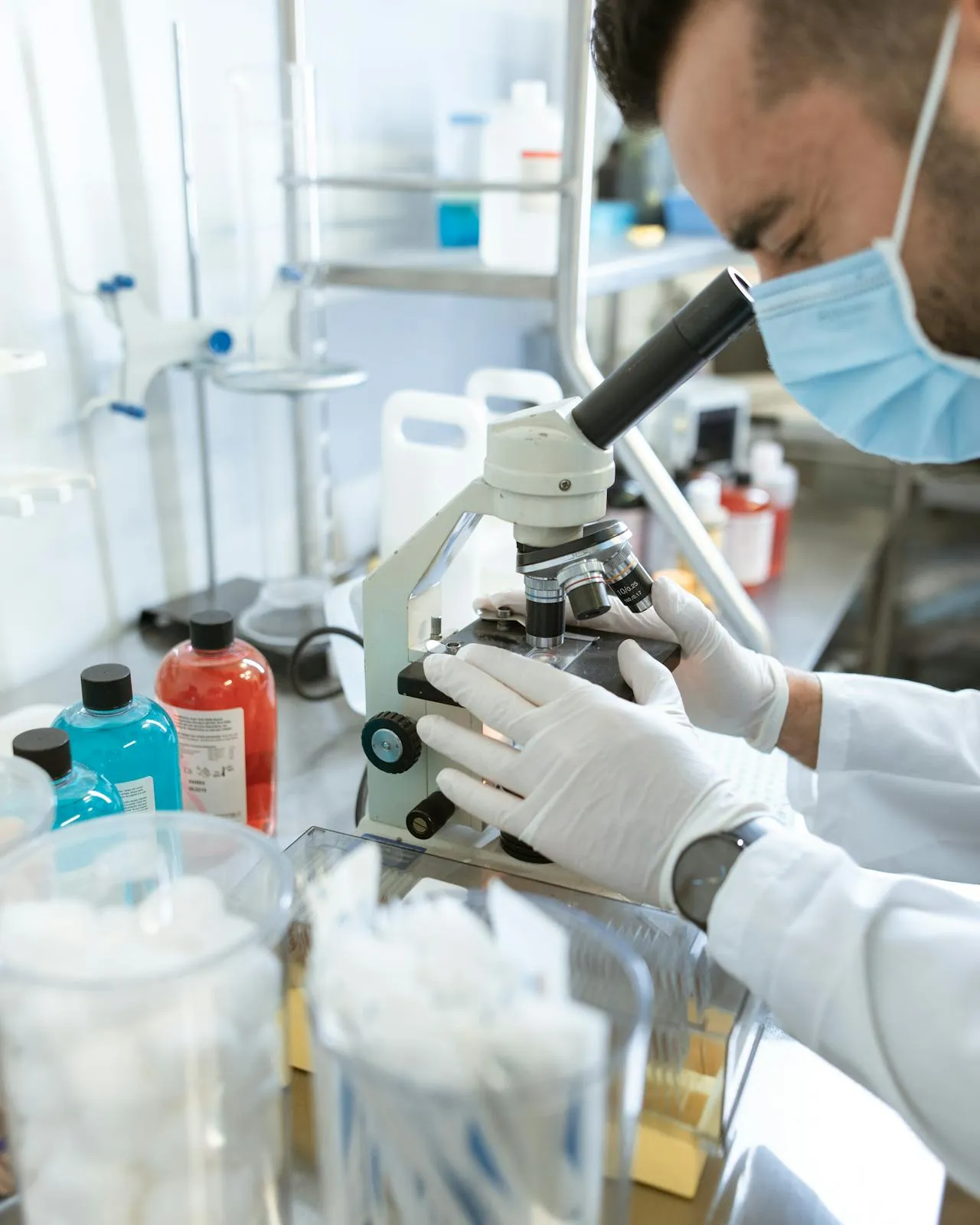 Home en un laboratori mirant per un microscopi 