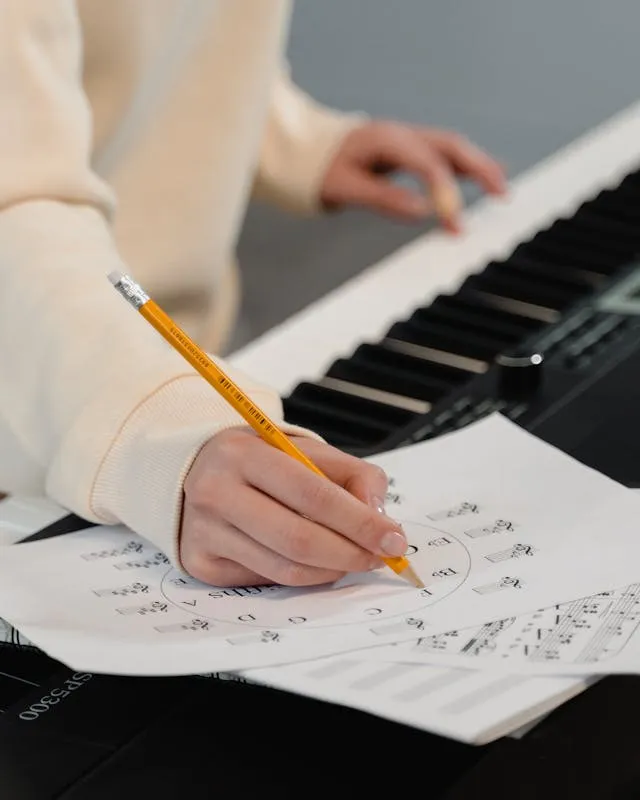 Persona amb un piano escrivint en una partitura Persona amb un piano escrivint en una partitura