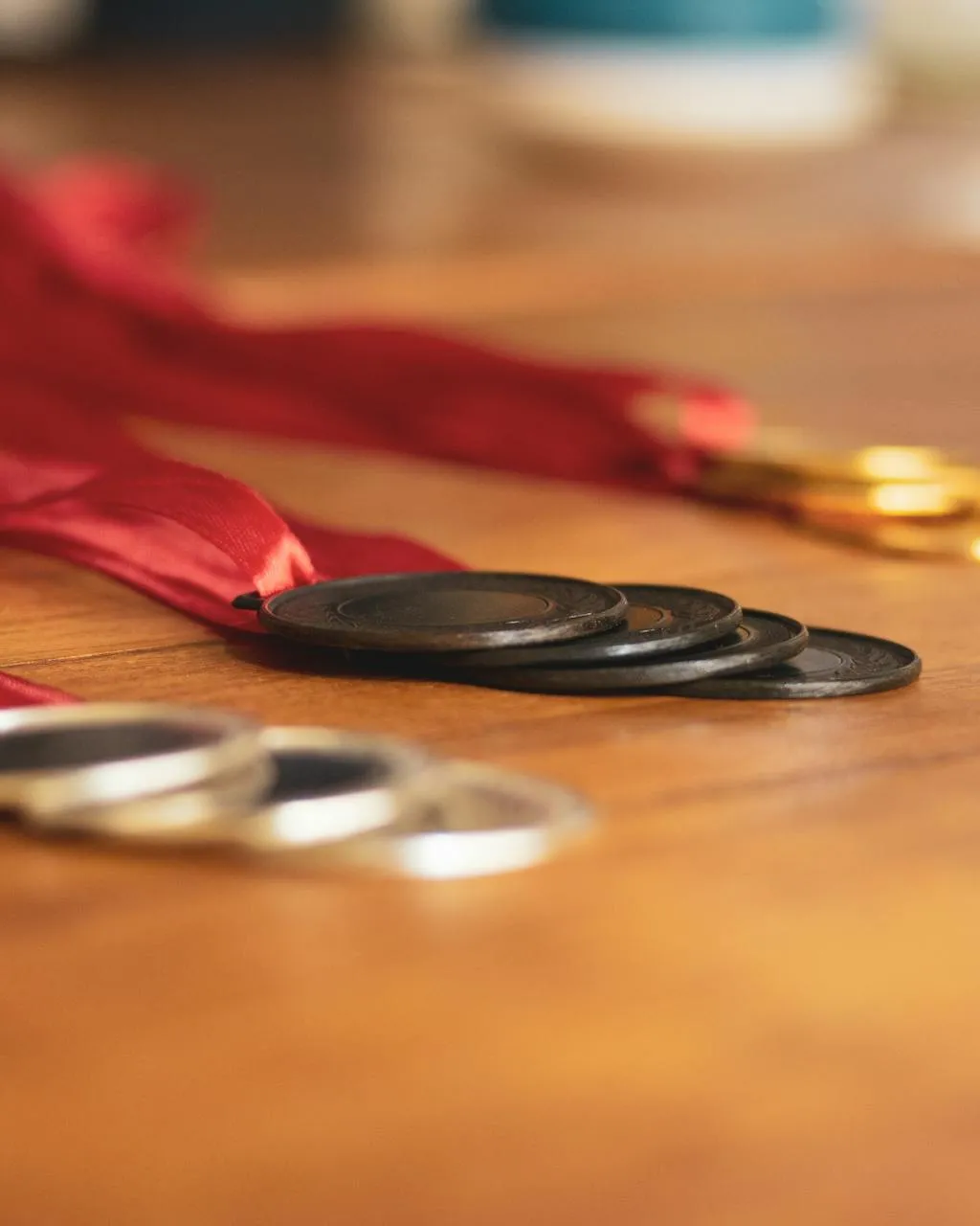 Plànol de prop de medalles d'or, plata i bronze amb cintes vermelles sobre una taula de fusta.