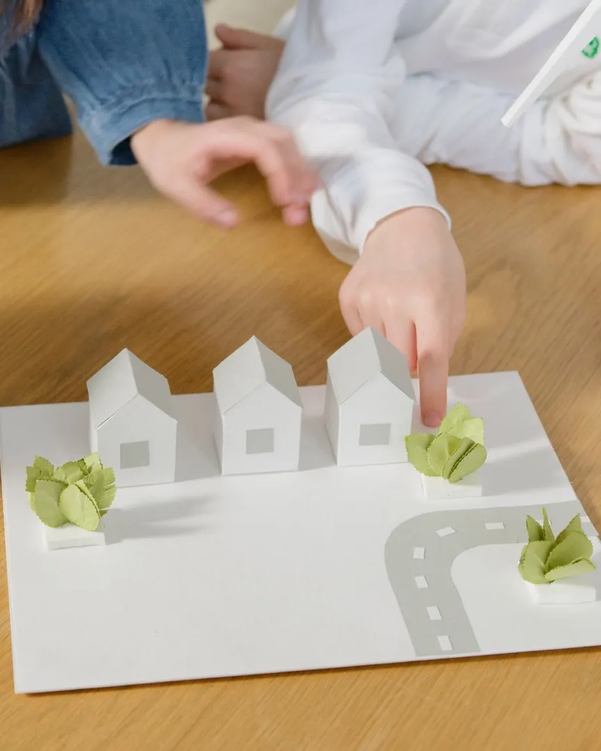 Infants interactuant amb un model de paper de cases ecològiques
