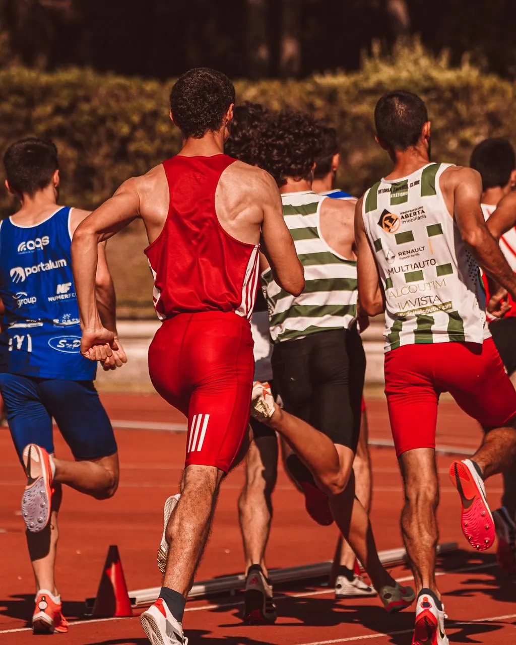 Un grup d'atletes masculins competint en una prova d'atletisme a l'aire lliure.