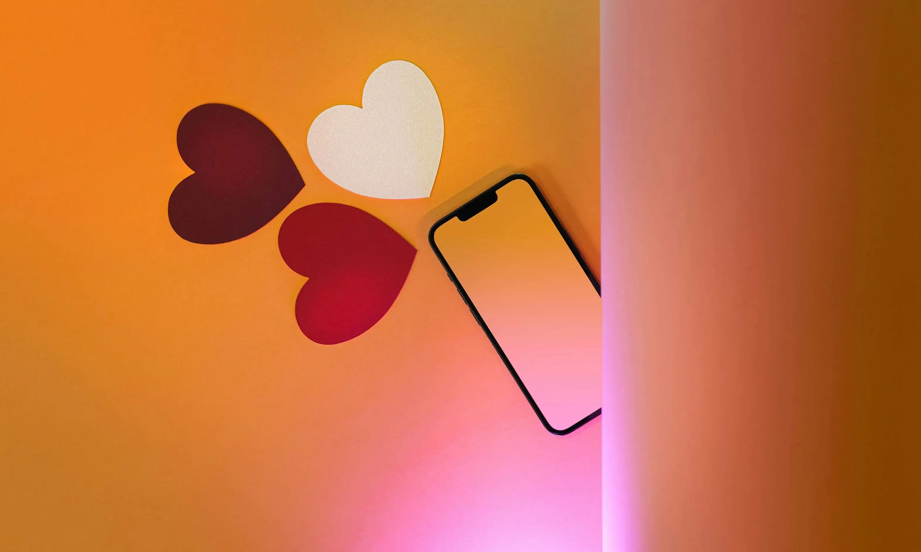 Mòbil sobre una superfície amb cors de paper al voltant. 