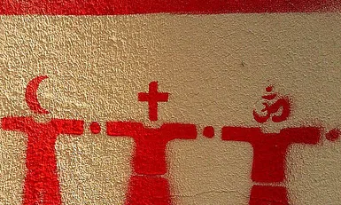 Imatge d'un grafiti amb persones que al cap tenen un símbol religiós