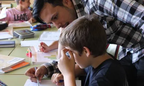 Voluntari amb un dels nens al taller de repàs del CROMA (Font: FAS)