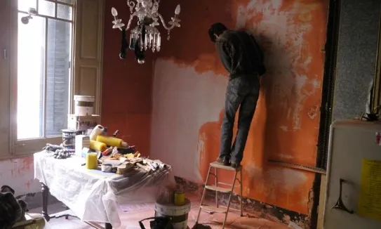Una jove rehabilitant la paret d'un domicili (Font: La Mula)