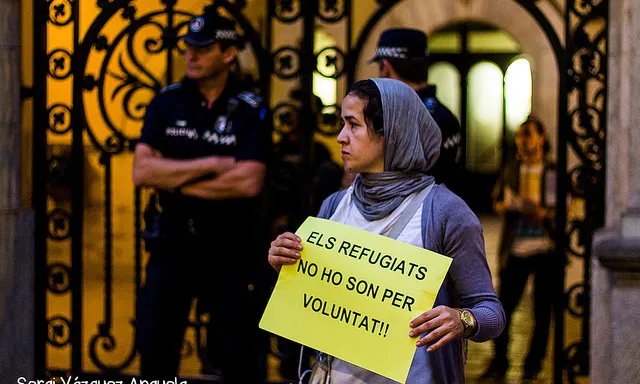 Dona musulmana amb un cartell que du escrit "Els refugiats no ho són per voluntat" (Autor:Sergi Vázquez Anguela. Font: flickr.com)