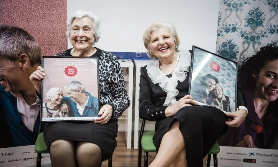 Dues dones grans presentant la campanya Roses contra l'oblit