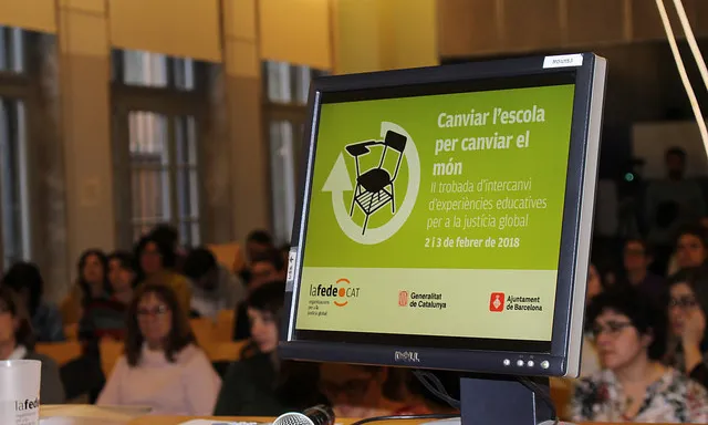 Un ordinador que mostra la diapositiva de presentació de la II Trobada 'Canviar l'escola per canviar el món'