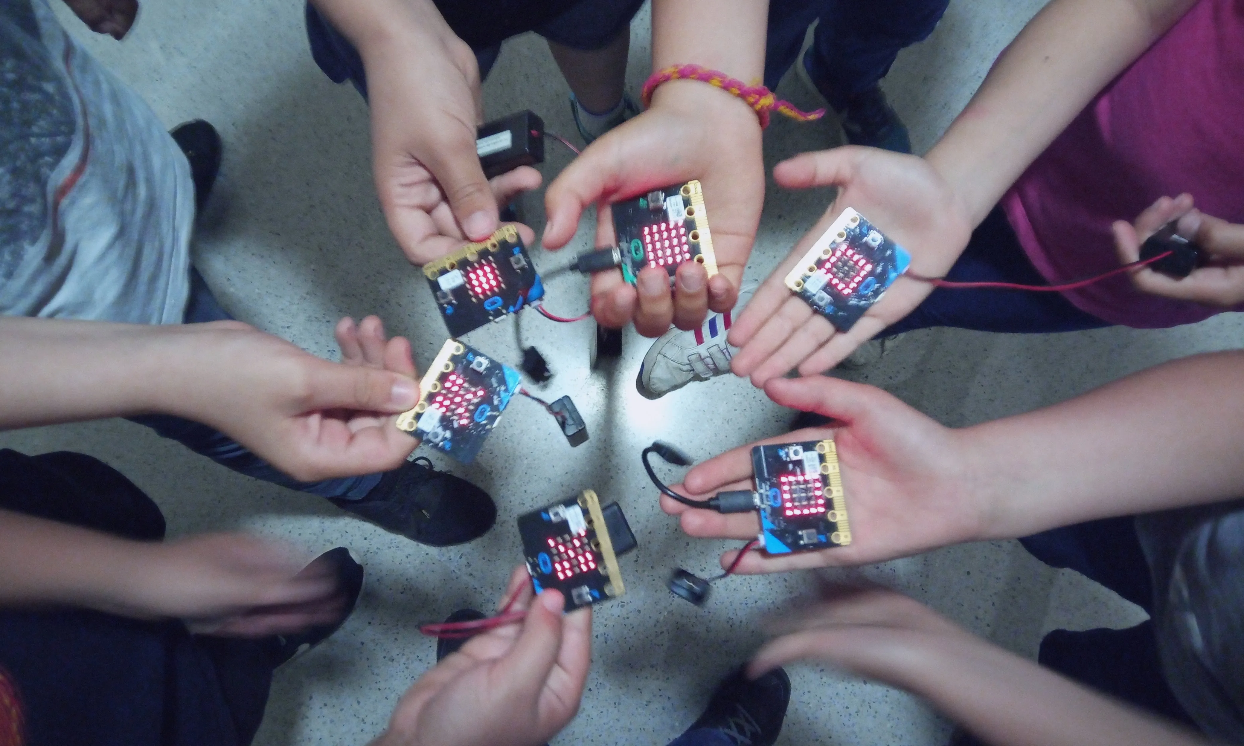 Mans de joves amb plaques de Micro:bit en un curs impartit per Colectic