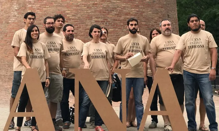 Membres d'ANA darrere del rètol amb les lletres de l'entitat