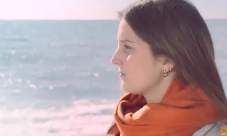 L'Àngela, amb 20 anys, camina per la platja.
