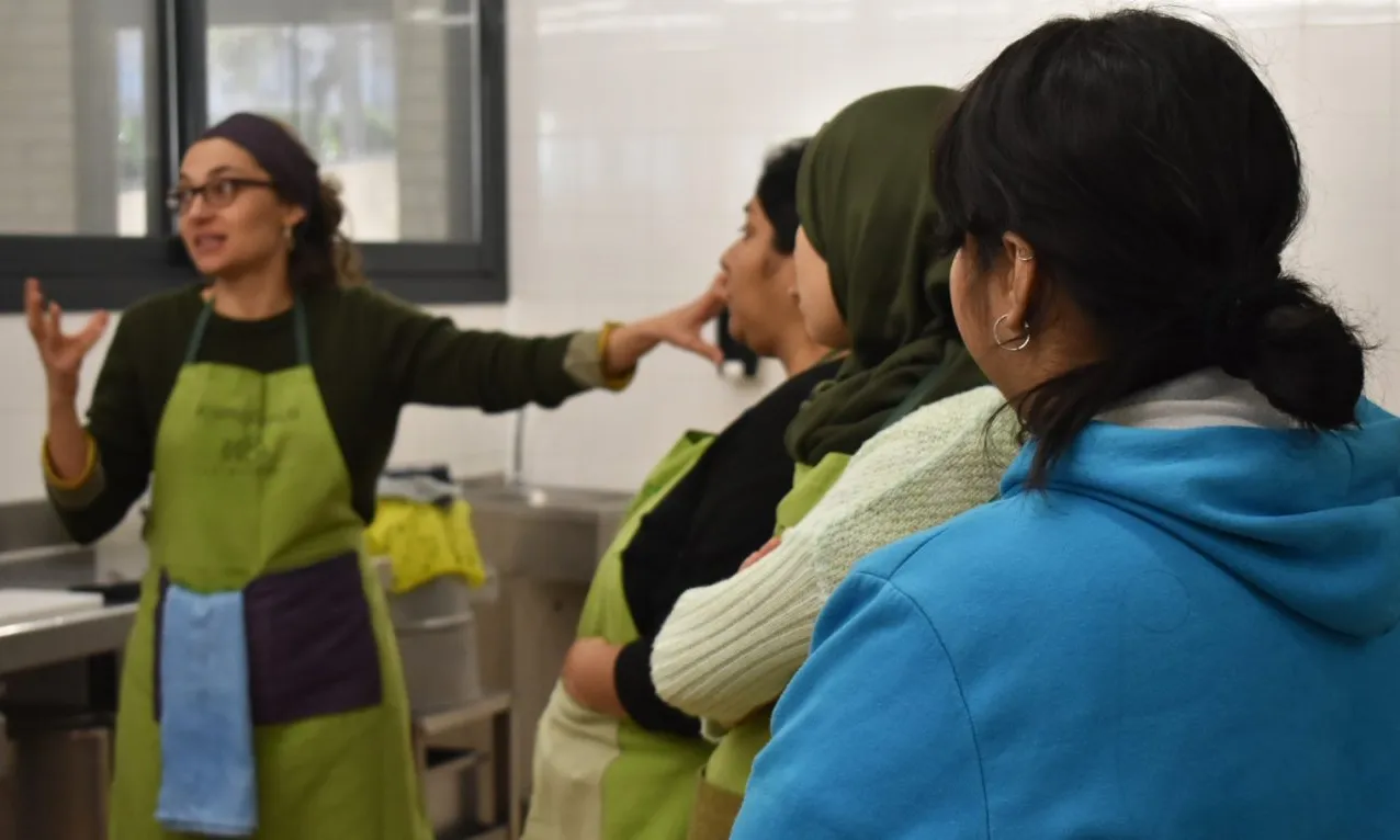 Tres participants en el taller escolten a la tallerista