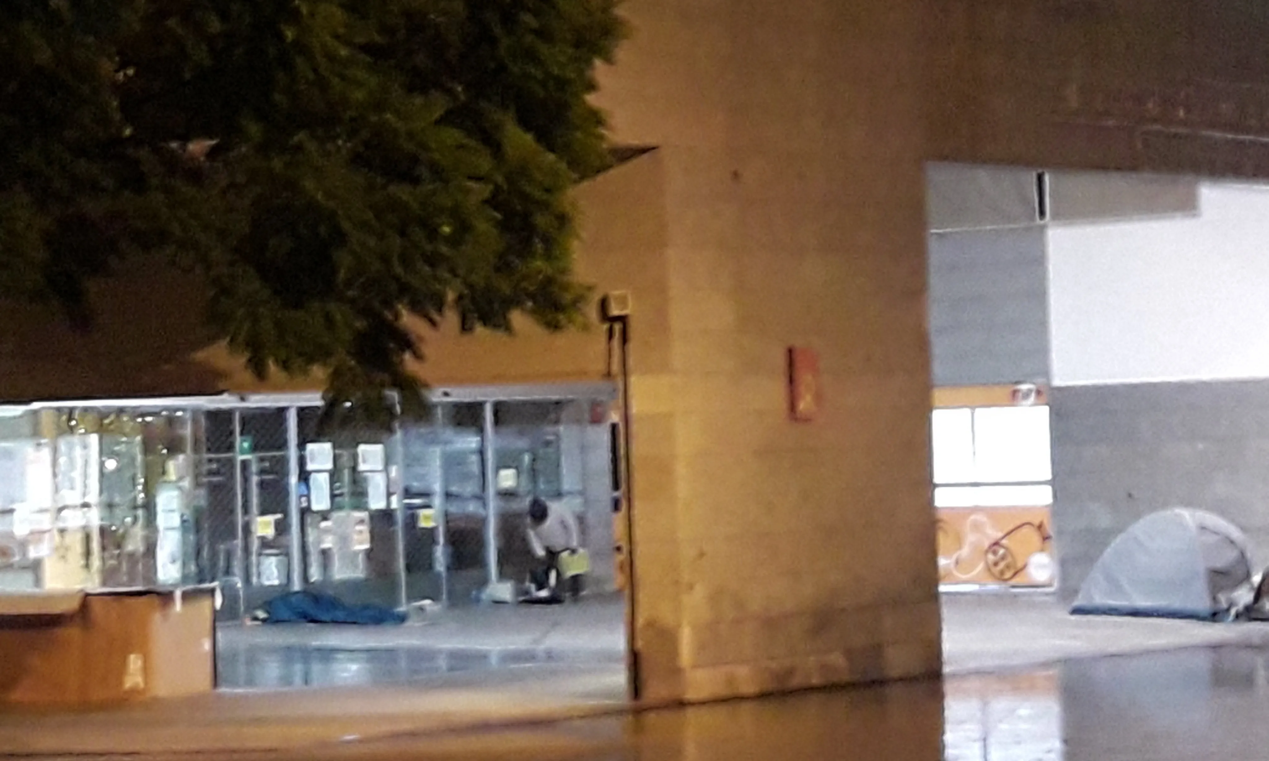 Persones dormint en una plaça de l'Eixample, a Barcelona, una nit de pluja.