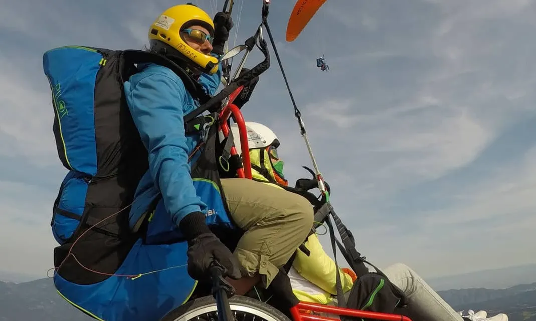 Una persona amb cadira de rodes fent parapent.