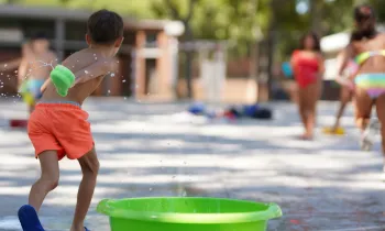 Un nen juga amb aigua en una activitat de lleure infantil estival