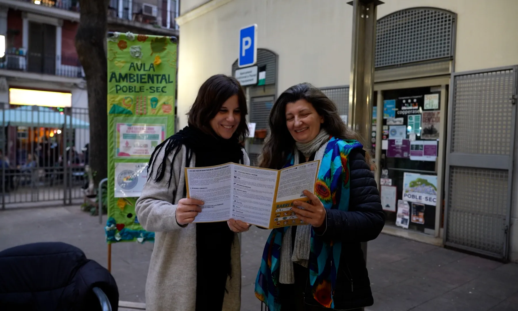 Dues dones mirant un tríptic de la seva entitat, Som la Clau.