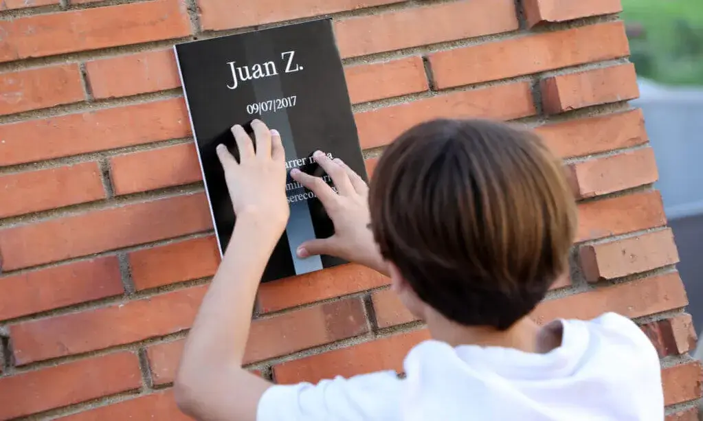 Nen voluntari penjant un dels cartells d'Arrels Fundació per rememorar les víctimes del sensellarisme