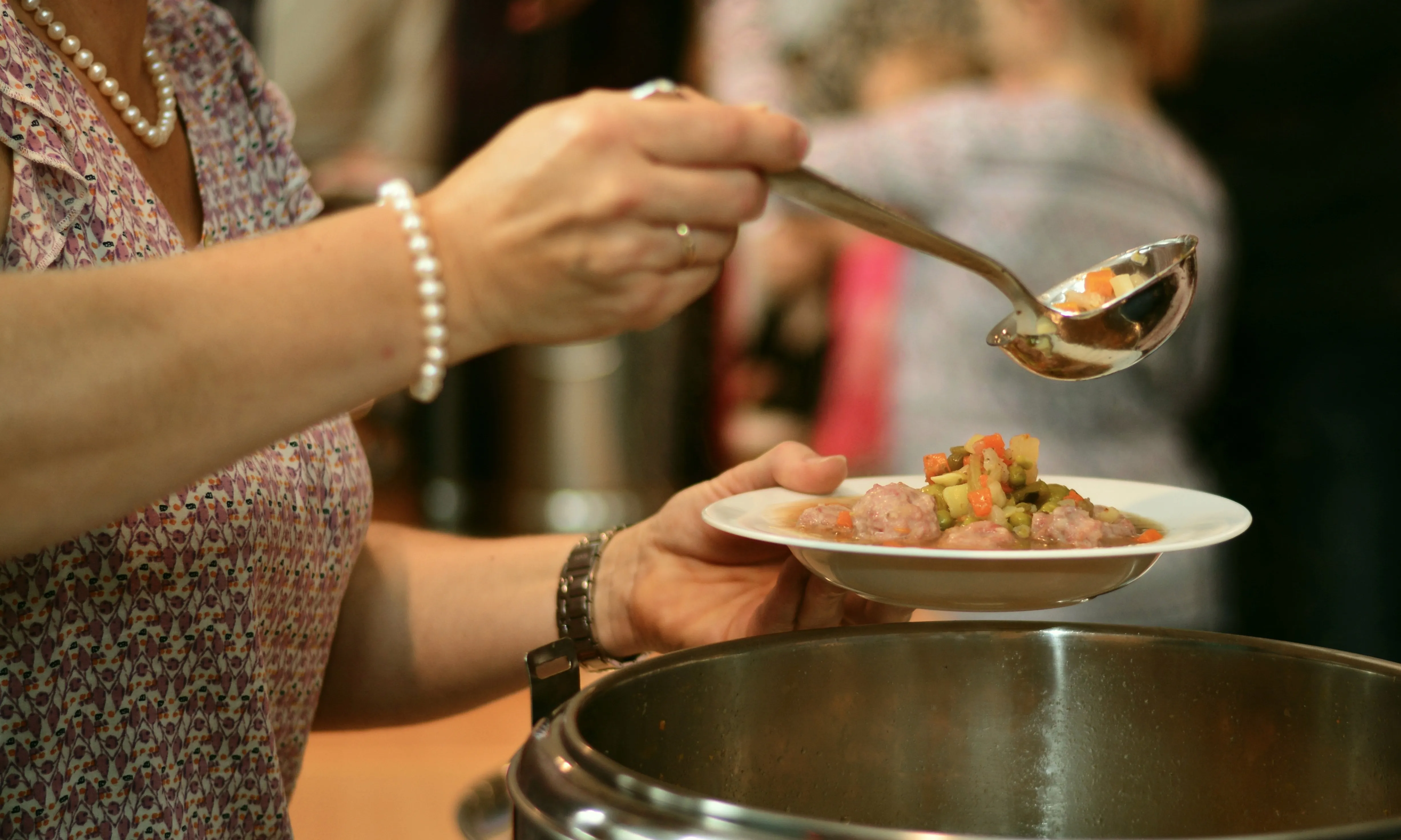 Imatge d'una persona servint menjar a un menjador social