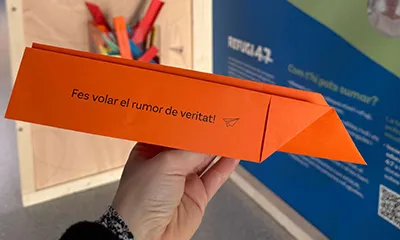 Avió de paper on hi ha escrit Fes volar el rumor de veritat!