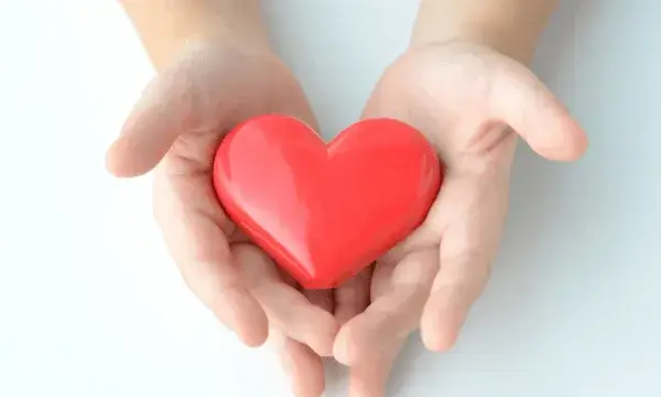 Dues mans sostenen un cor vermell, símbol de solidaritat i suport a causes socials.