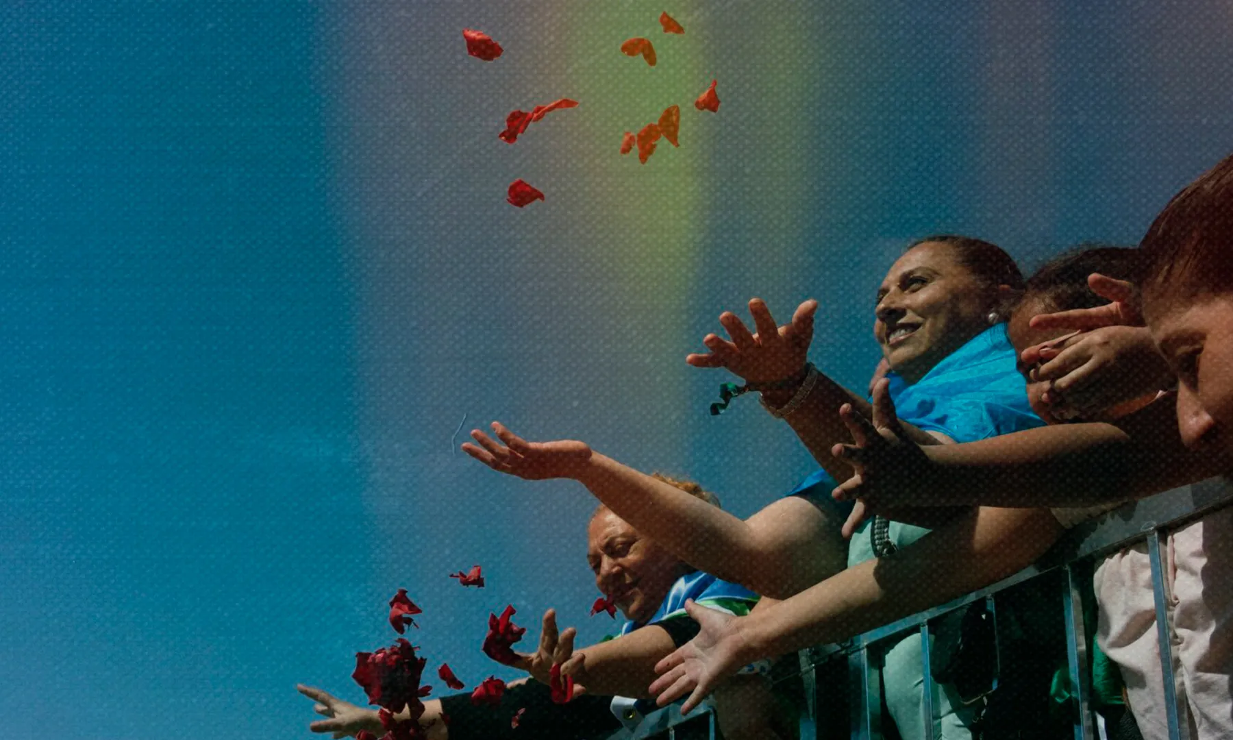 Persones llancen pètals de flors des d’un balcó durant una celebració a l’aire lliure.