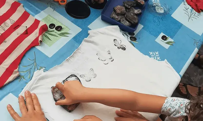 Imatge amb mans infantils estampant papallones a una tela.