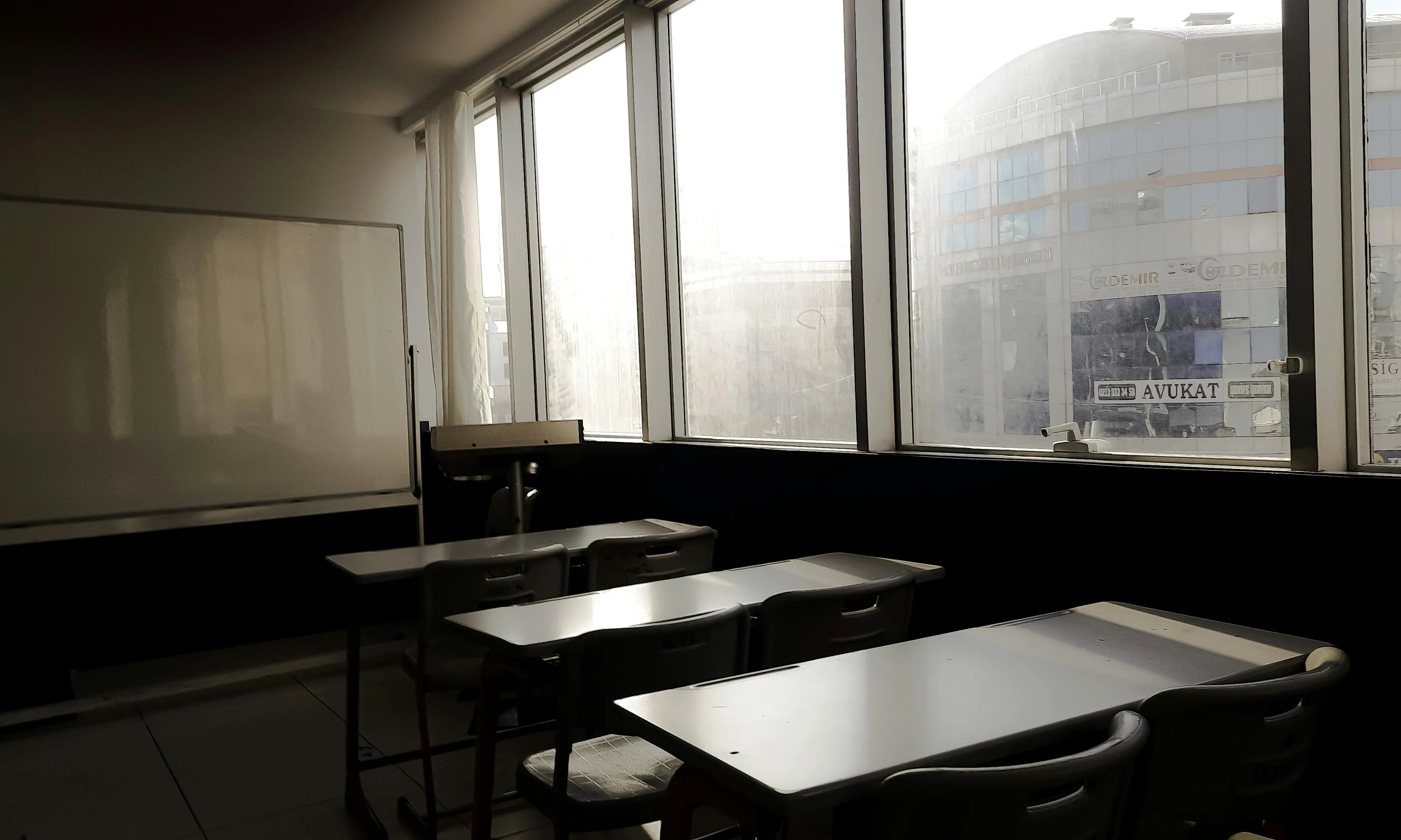 Una aula amb pupitres davant una finestra. 