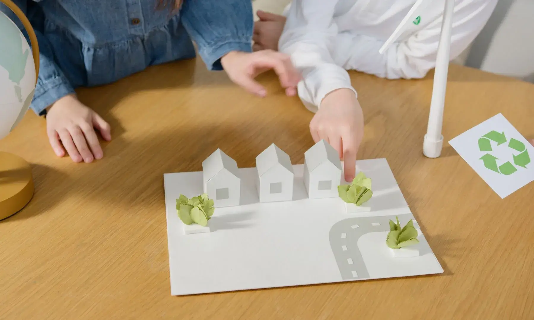 Infants interactuant amb un model de paper de cases ecològiques