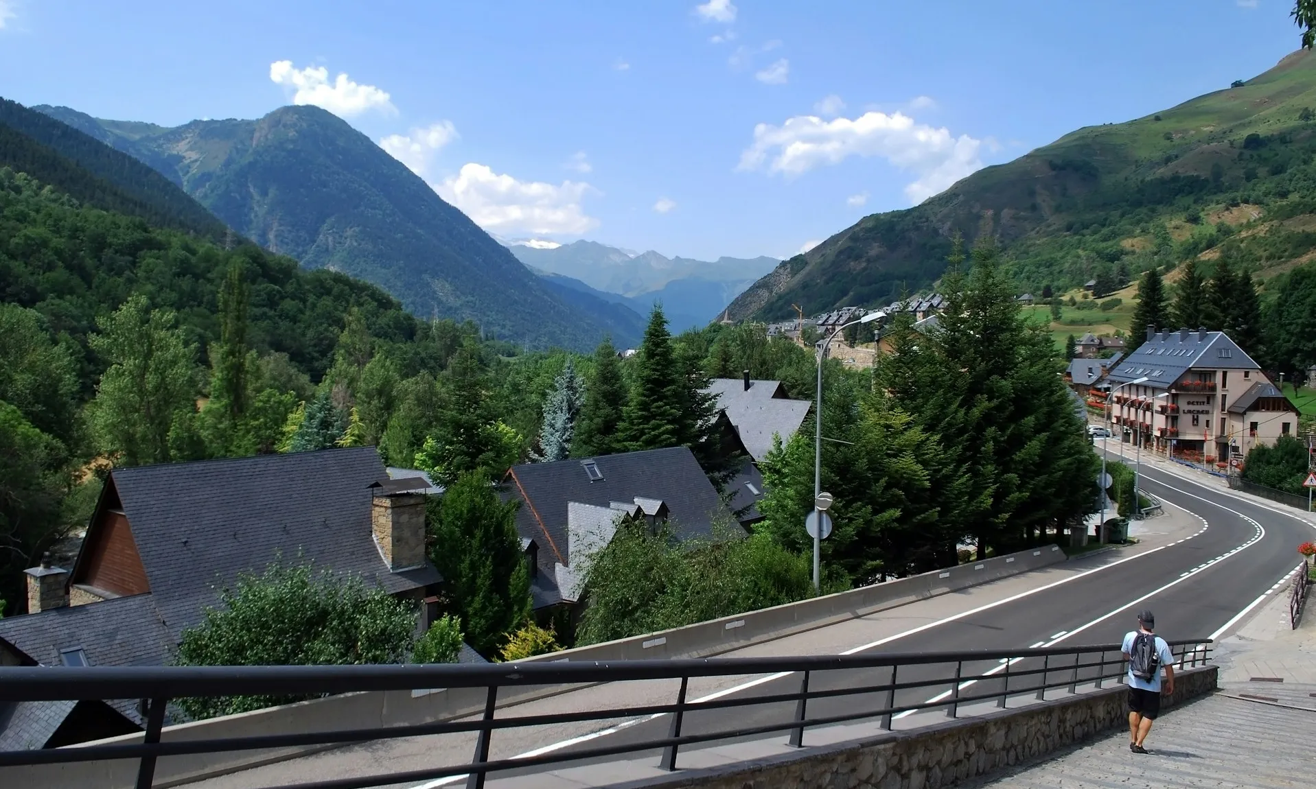 Home caminant per unes escales de formigó amb Salardú (Vall d'Aran) de fons.