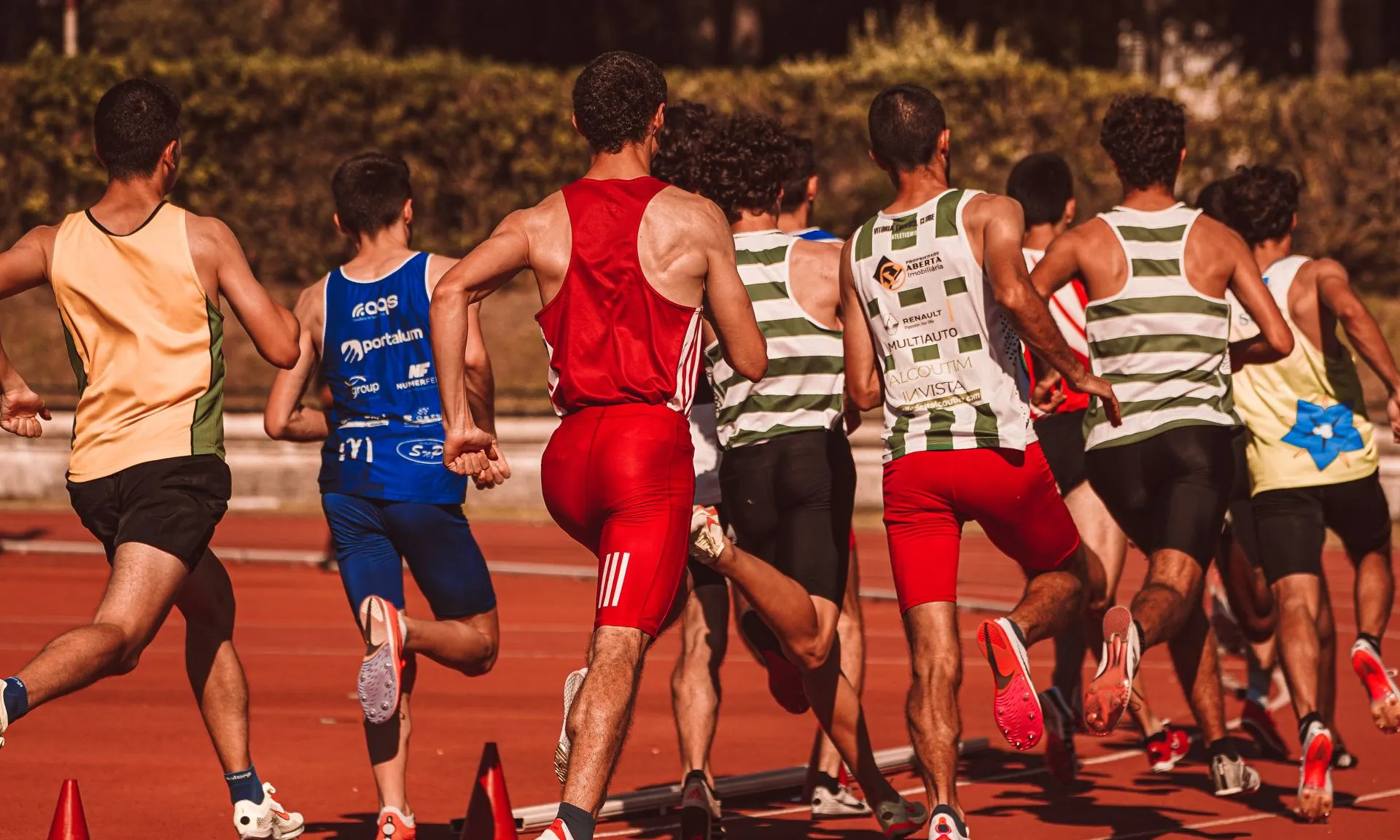 Un grup d'atletes masculins competint en una prova d'atletisme a l'aire lliure.