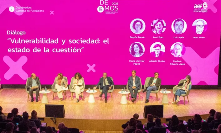 Una de les taules rodones del Demos 26, amb les 6 persones participants i la moderadora al davant d'un fons rosa amb el títol de la taula. 