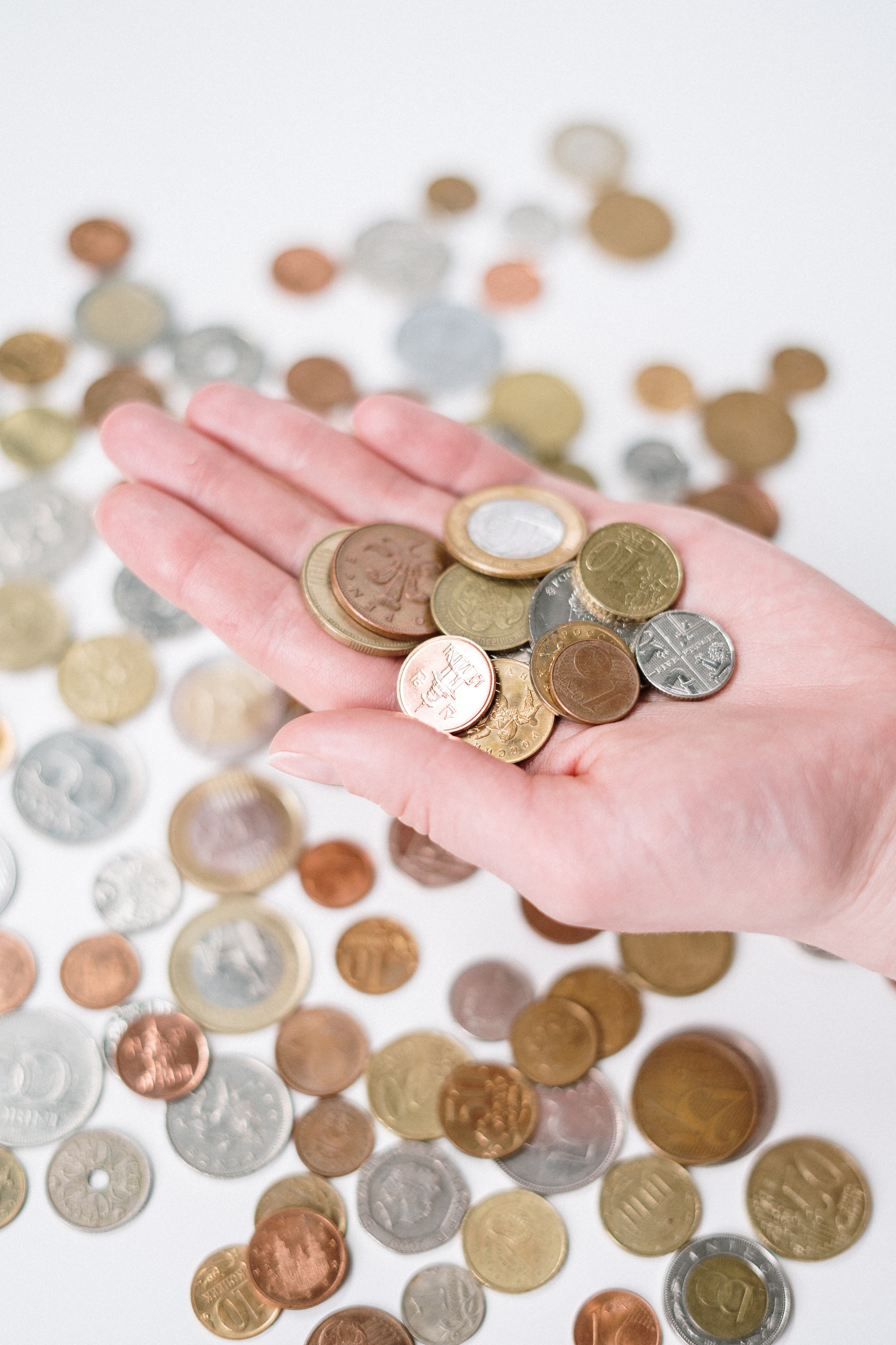 Taula amb monedes d'Euro i mà agafant-n'he. Font: Pexels - cottonbro studio