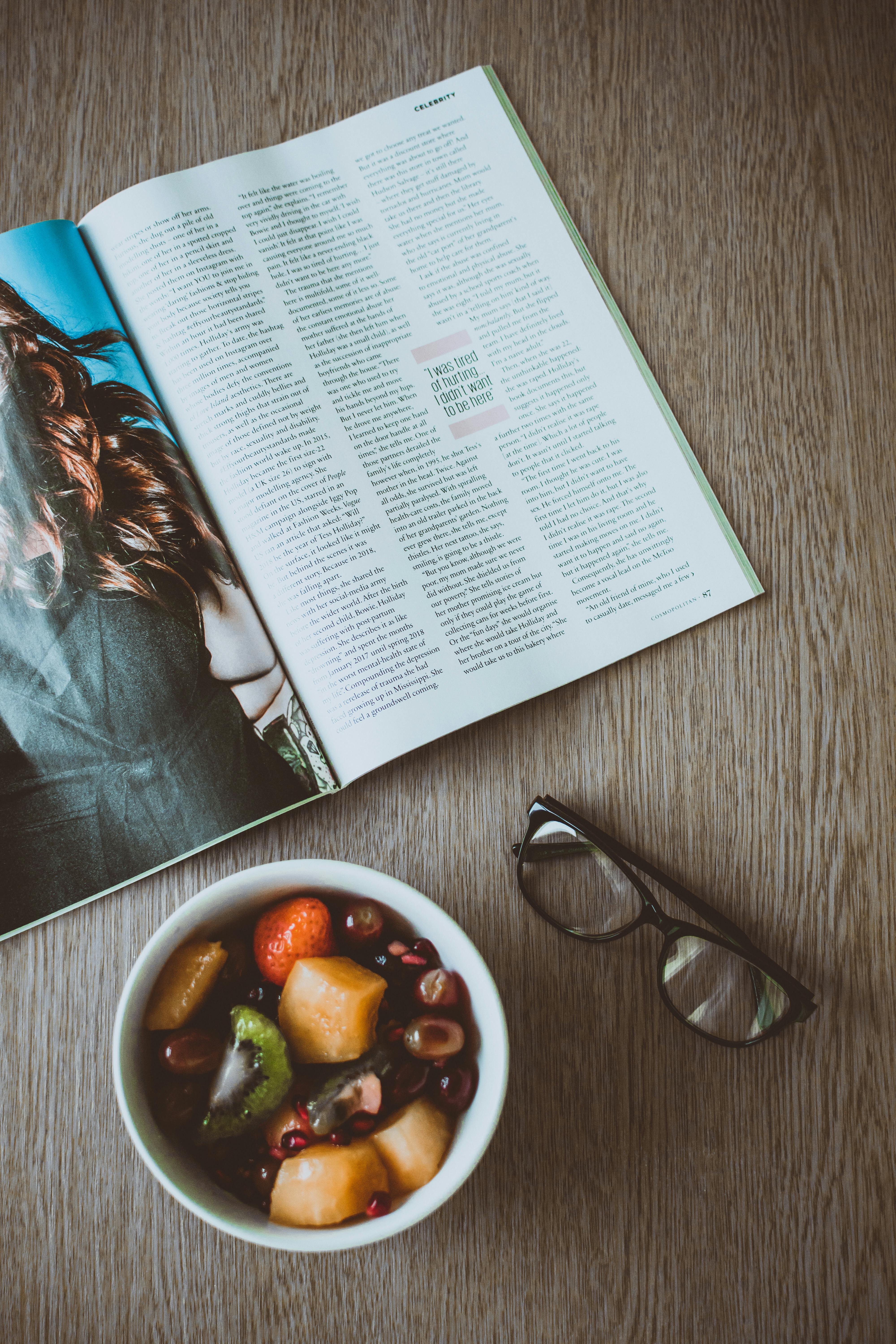 Taula amb una revista, unes ulleres i un bol amb menjar. Font: Pexels - Lisa Fotios 
