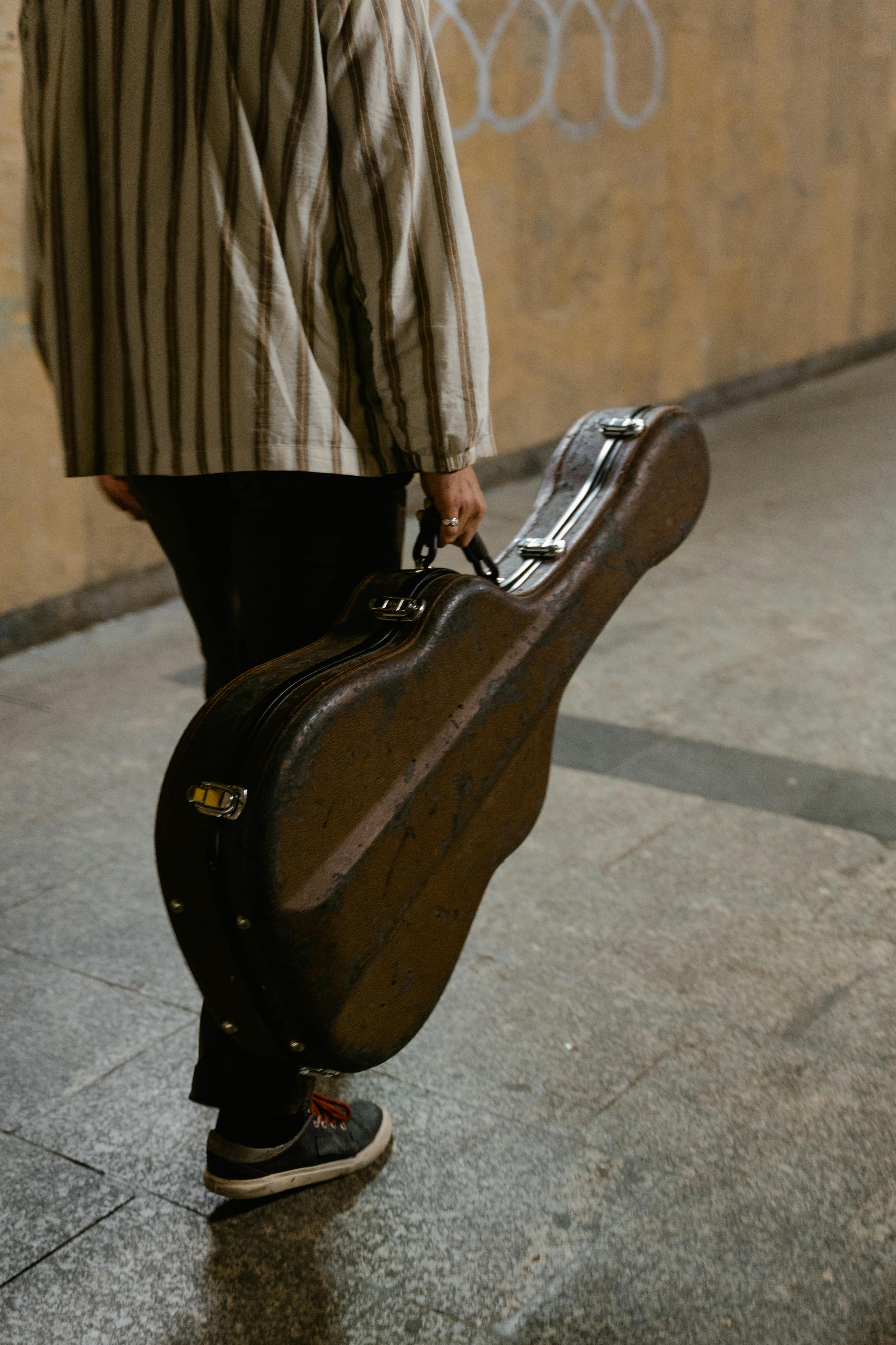 Persona transportant una guitarra en un metro. Font: Pexels - MART PRODUCTION