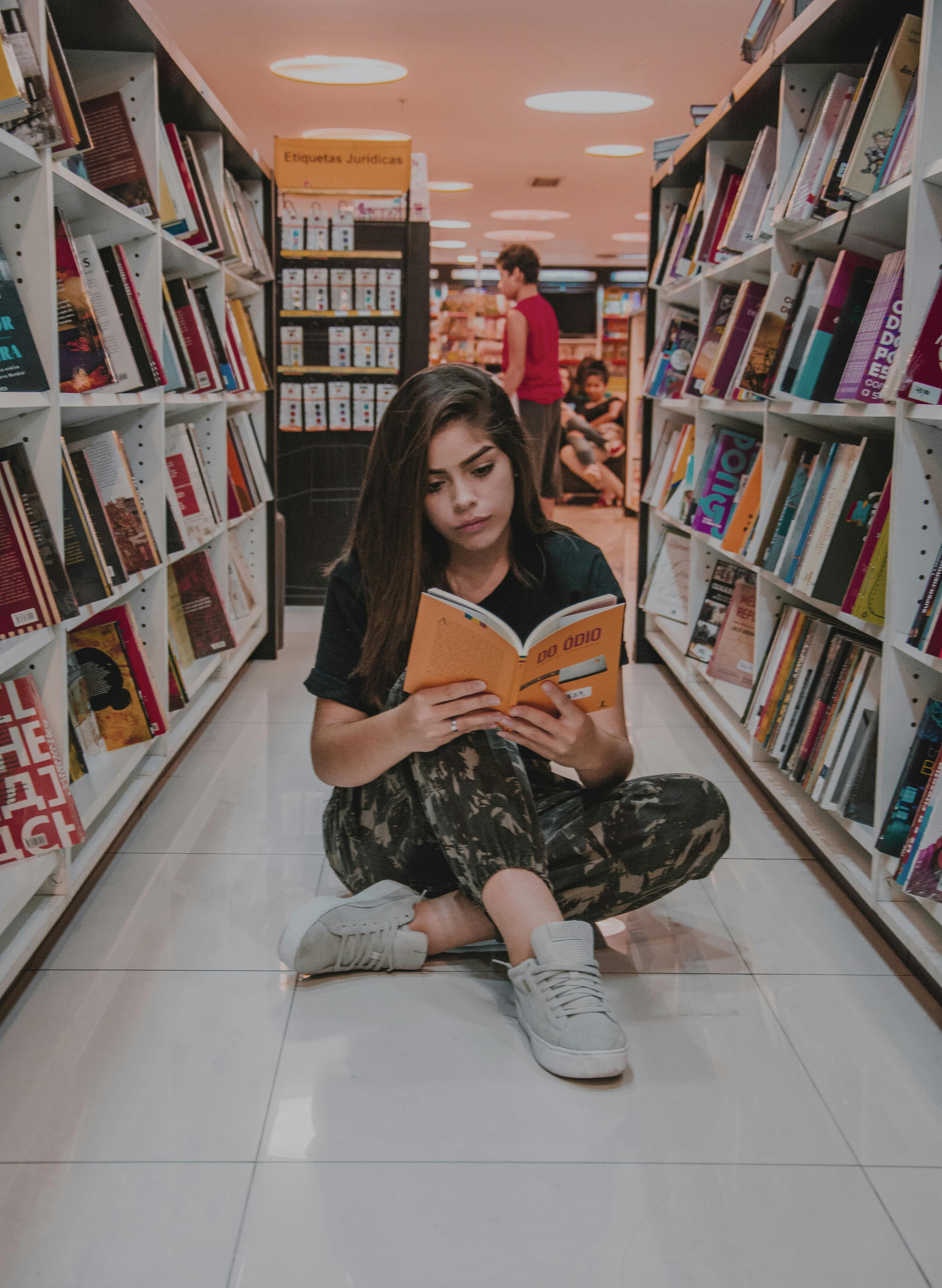 Noia llegint una revista a una biblioteca. Font: Pexels - Nicole Berro