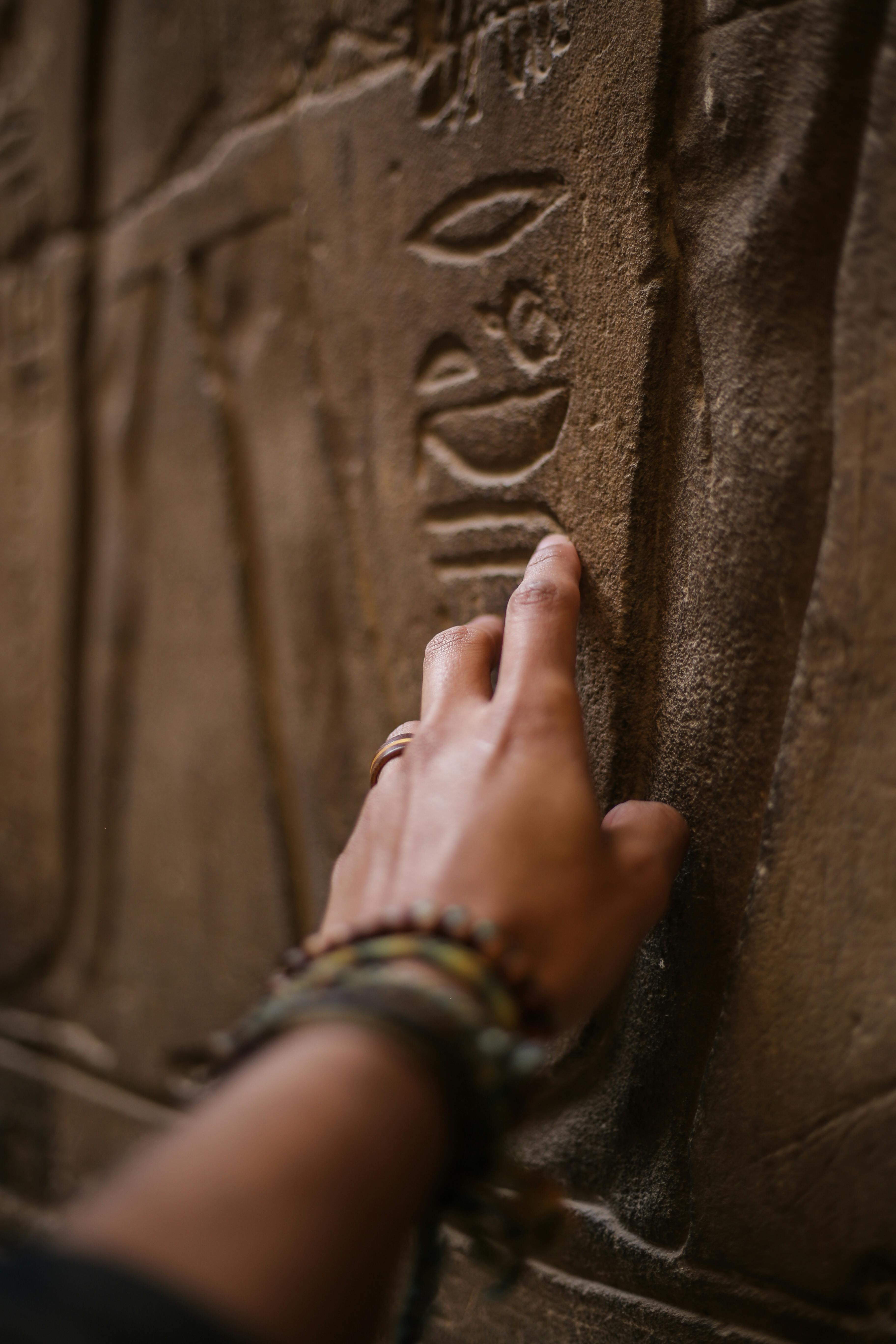 Mà tocant una escriptura en pedra egípcia. Font: Pexels -Oziel Gómez