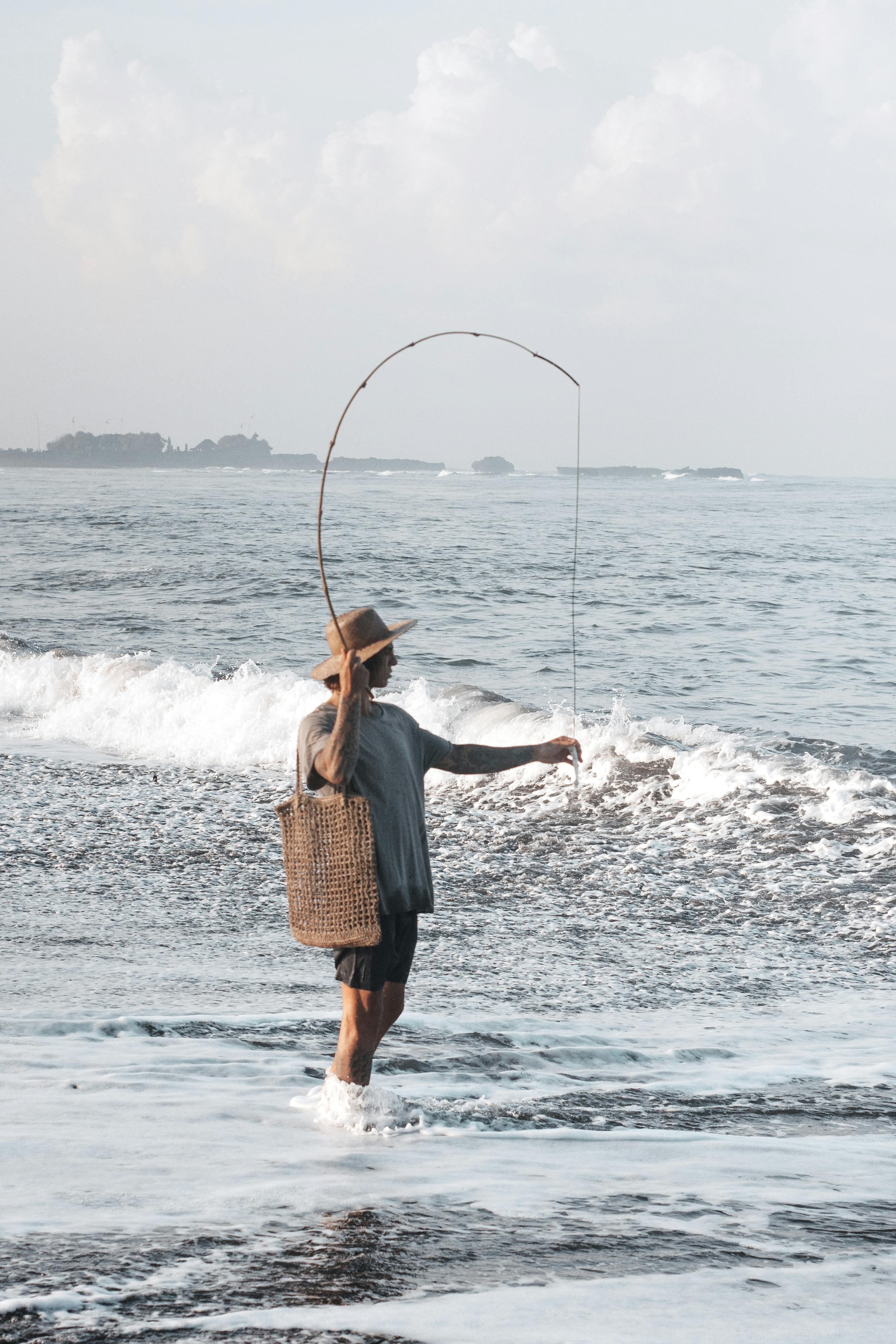 Noia pescant a la platja. Font: Pexels - ROMAN ODINTSOV
