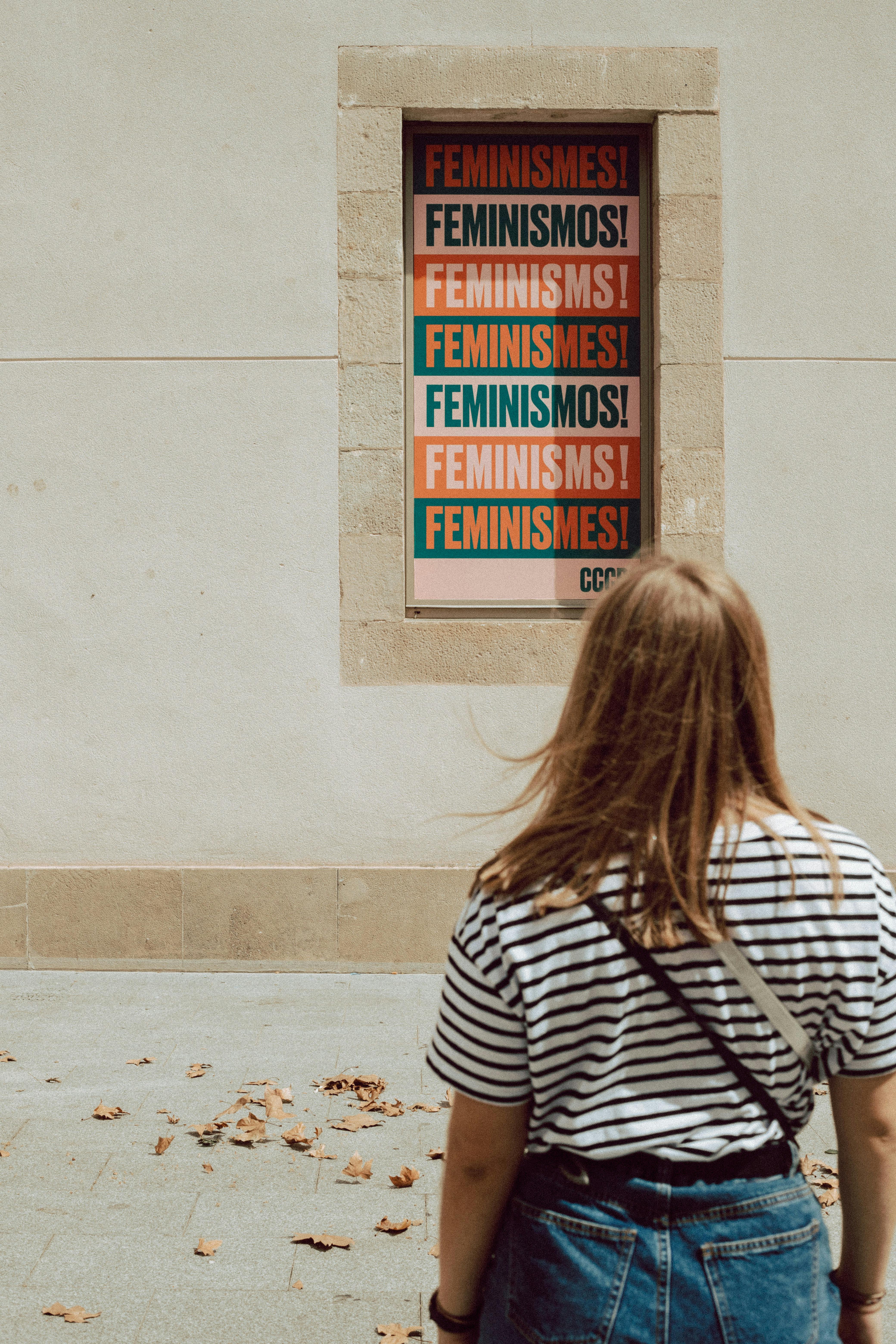 Noia mirant un cartell on posa feminisme en diferents idiomes. Font: Pexels - Sinitta Leunen