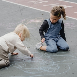 Dos nens dibuixant al terra. 