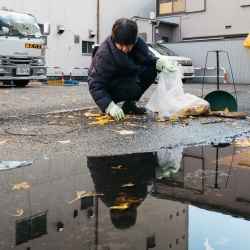 Una persona voluntària recull brossa reflectida en un bassal d'aigua.