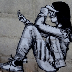 Un graffiti en que apareix una persona jove amb el seu telèfon mòbil.