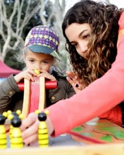 Voluntària del 'Posa't la Gorra' juga amb una nena. Font: AFANOC