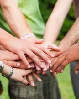 Persones voluntàries fan pinya amb les mans després d'una activitat. Font: Xarxanet