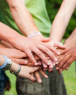 Persones voluntàries fan pinya amb les mans després d'una activitat. Font: Xarxanet