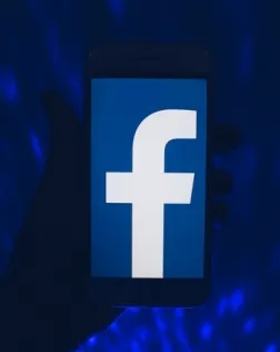 Fotografia d'una persona utilitzant un telèfon mòbil amb l'aplicació Facebook. 