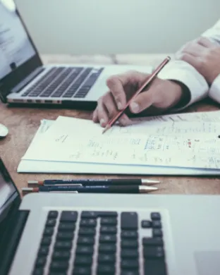 Persones treballant i analitzant documents com a representació del webinar 'El compliment normatiu de les fundacions. Una forma de funcionar, més enllà de les obligacions legals'. Font: Unsplash