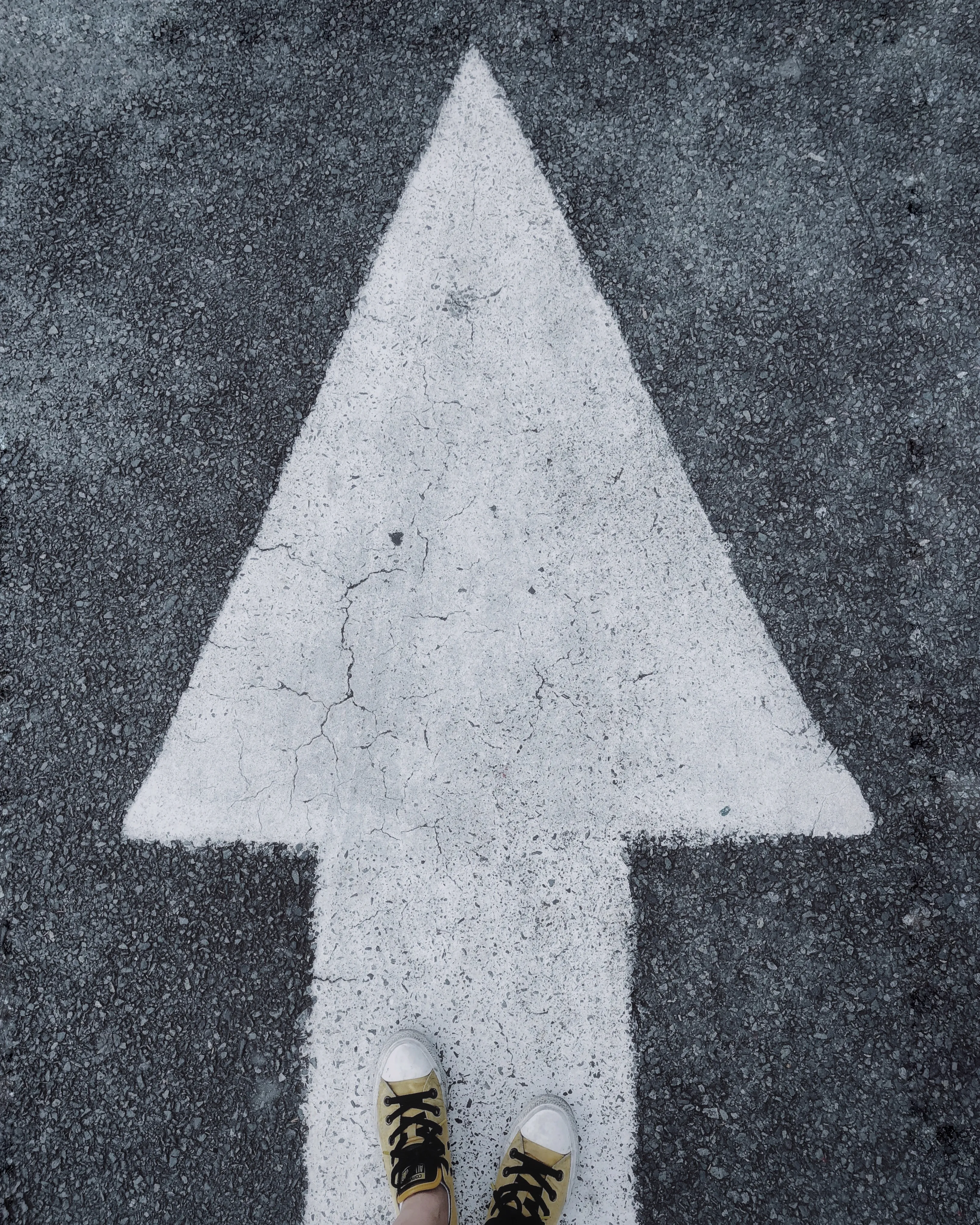 Persona seguint una fletxa a la carretera. Font: Pexels - Vicky Tran