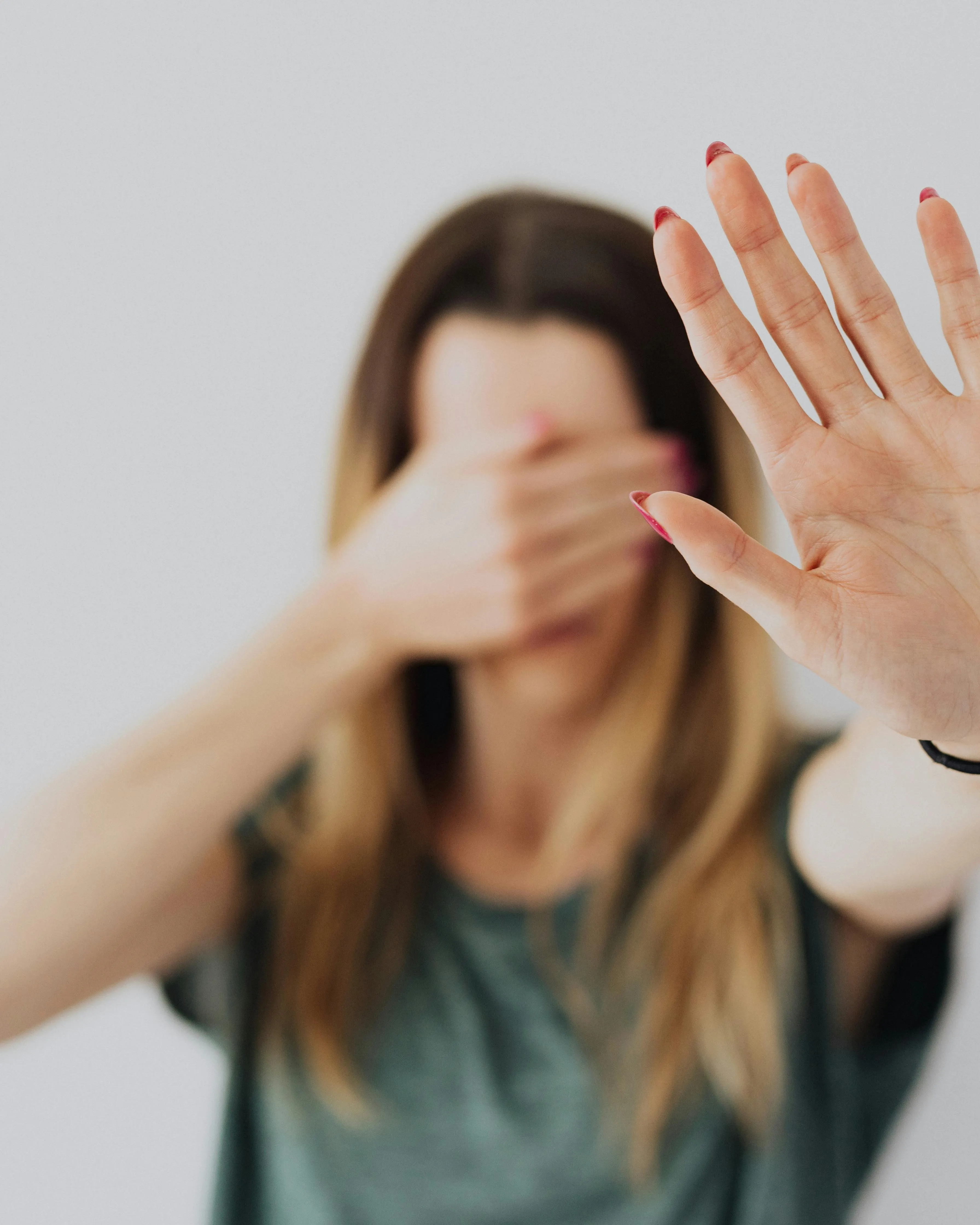 Dona fent senyal de parar i tapant-se els ulls. Font: Pexels - Karolina Grabowska